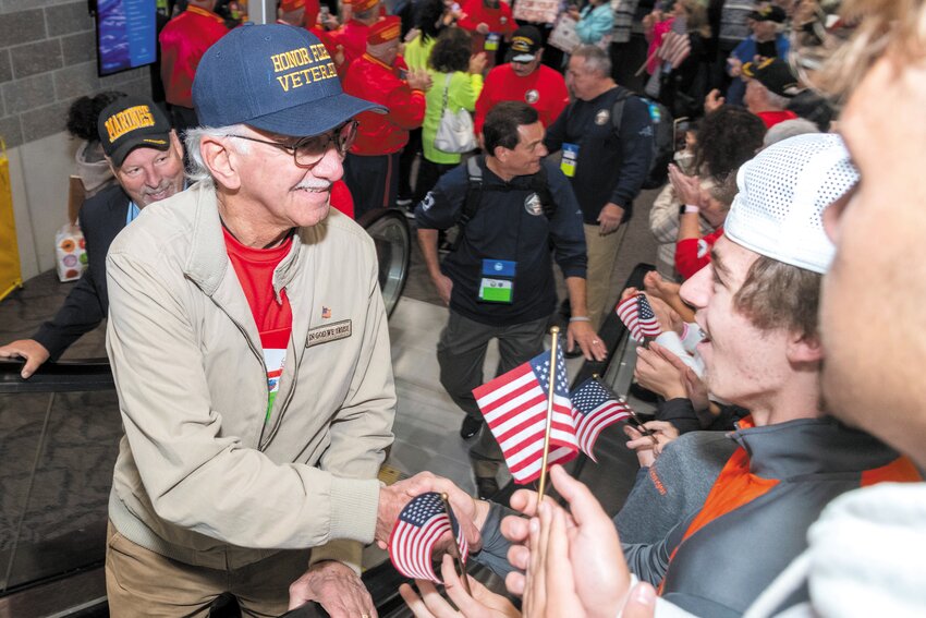 AMONG FRIENDS: Veteran John Martino is thanked for his service as he rides the escalator at Green Airport in preparation for Sunday&rsquo;s Honor Flight to Washington.  At left is Pastor Frank Reedy of Sacred Exchange Fellowship in East Greenwich, sponsors of Honor Flight &quot;Hope&quot;  Who is a US Marine Corp veteran also participated in the Wreath Ceremony.  (Photos courtesy of the RI Airport Corporation)