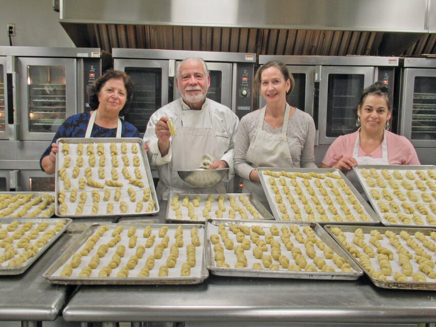 KITCHEN KREW:  Jim Harritos is ready to cover this tray of Kouroulakia &ndash; a.k.a. Greek sesame cookies that Elizabeth Degaitas, his wife Nancy Haritos and Hoda Daiaa later baked for this weekend&rsquo;s Christmas Bazaar and Food Fair that will be held this weekend in Cranston. (Herald photos by Pete Fontaine)