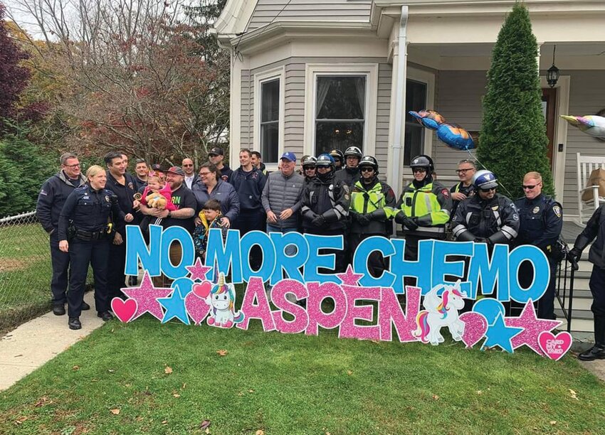 NO MORE CHEMO: Aspen, as well as Mayor Ken Hopkins and the members of Enzo&rsquo;s Escorts pose at the sign which greeted Aspen on her return home. (Photos provided by Cranston PD)