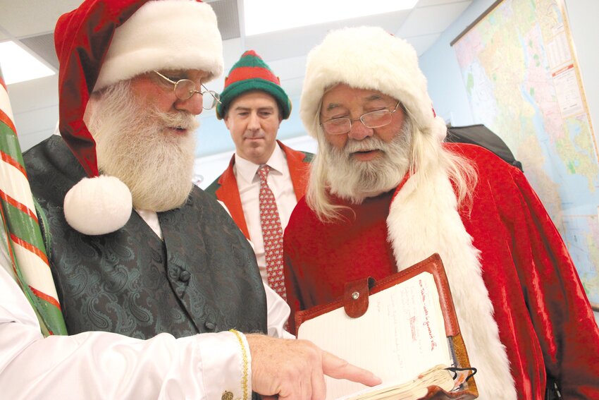 WHO'S NAUGHTY, WHO'S NICE: Santa Dave Bennett and Santa Paul Evans compare notes as Elf Matt LaMountain looks on, during photos with Santa on Saturday at the Warwick Beacon. (Warwick Beacon photo)