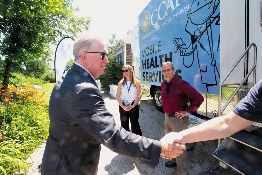 HANDSHAKES AROUND: Cranston Mayor Kenneth Hopkins arrives at Aspray Boat House, greeting a crowd including Warwick Mayor Frank Picozzi and CCAP Dental Manager Tara Pratt taking a look at the van.