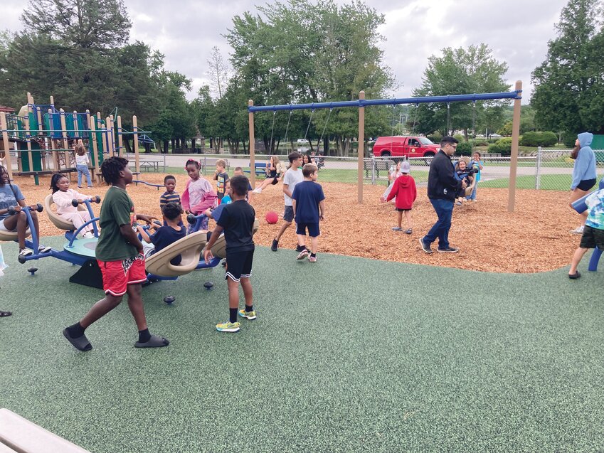 READY TO PLAY: Children from the Johnston Youth Summer Camp test out the new see-saw after Polisena and the Grieco family officially open the playground within Memorial Park.