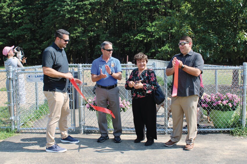 TRAVIS CUTS RIBBON: Councilwoman Travis, joined by Councilman McAllister and Mayor Picozzi, cuts the red ribbon with the ceremonial scissors in front of the large dogs play area.