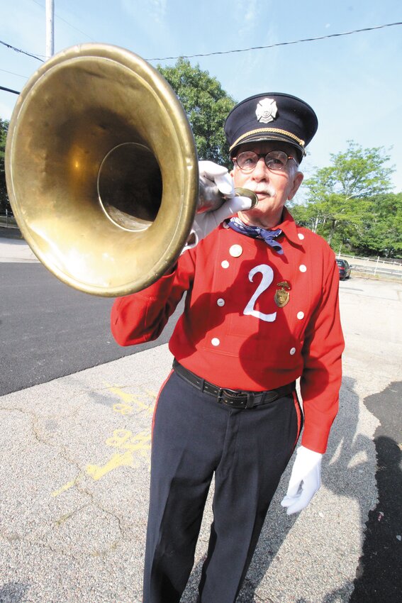 NOW, HEAR THIS: Harry Cohoon, wearing a firemen&rsquo;s woolen dress suit from the early 1900s, displays a fire trumpet from his collection of firefighting equipment. He said after fighting a fire, a stopper would be fitted into the mouth piece and the horn filled with beer that was passed around. (Warwick Beacon photos)