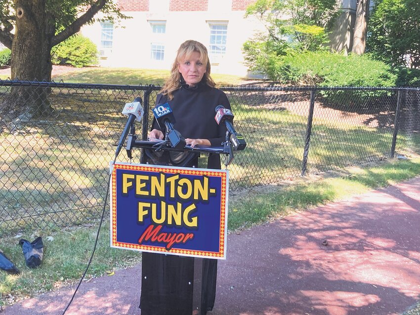 DOWN THE HOME STRETCH: Fenton-Fung, standing outside Cranston City Hall, calls for an investigation into Hopkins. Behind her are signs displaying text messages that Davide Broccoli alleges that Hopkins sent him.