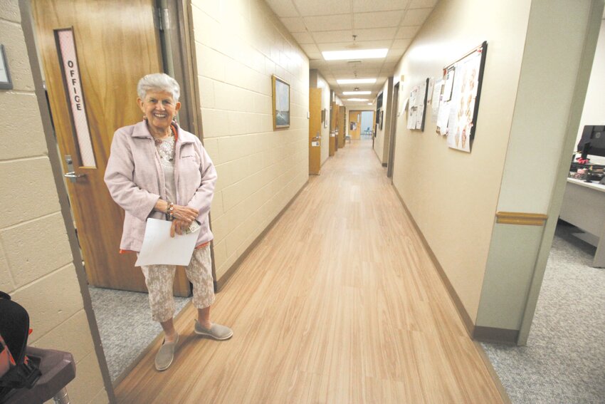 THE NEW LOOK: Pilgrim Senior Center volunteer Nancy Vileno greets visitors as they enter the newly floored corridor leading to the center foyer.