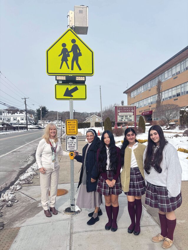 Sister Daisy Kollamparampil, St. Rocco Principal Melissa D&rsquo;Amico, and several of Sister Daisy&rsquo;s former students activate the new crosswalk traffic signal in front of the school and church.