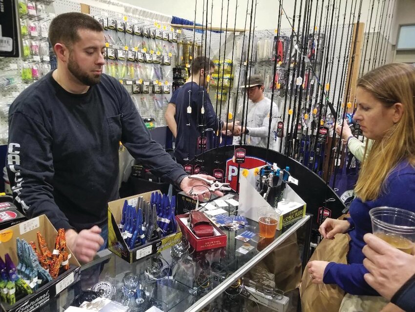 Nei Hayes of Quaker Lane Bait &amp; Tackle, North Kingstown, works with a customer at the New England Saltwater Fishing Show. Submitted photo