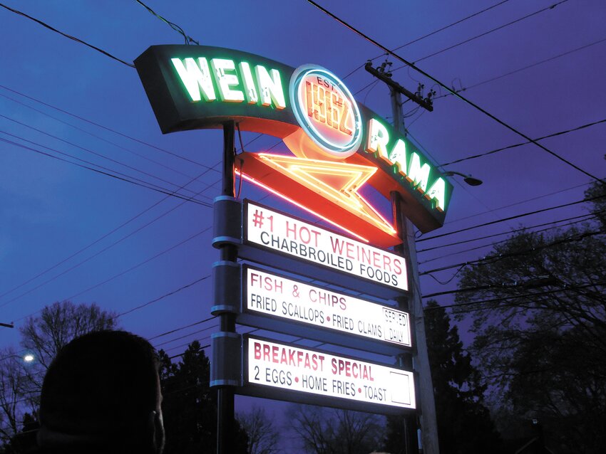 The newly restored Wein-o-rama sign lit up the night sky last Tuesday night as people looked on.