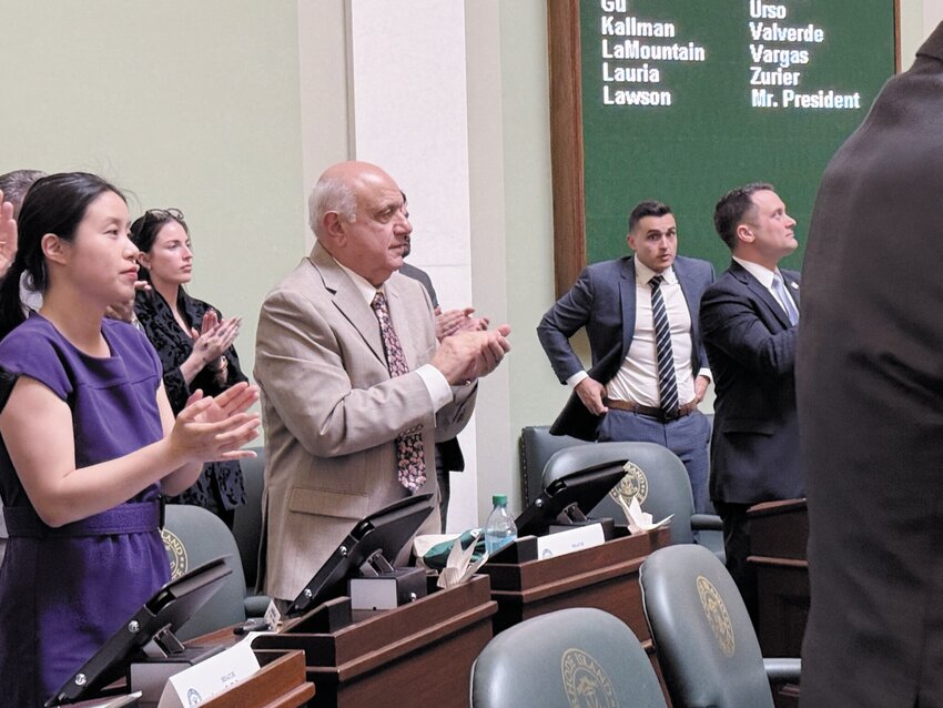 Sen. Frank Ciccone, in tan jacket, a Providence/Johnston Democrat, applauds on Tuesday. At left is Sen. Victoria Gu, a Westerly Democrat.