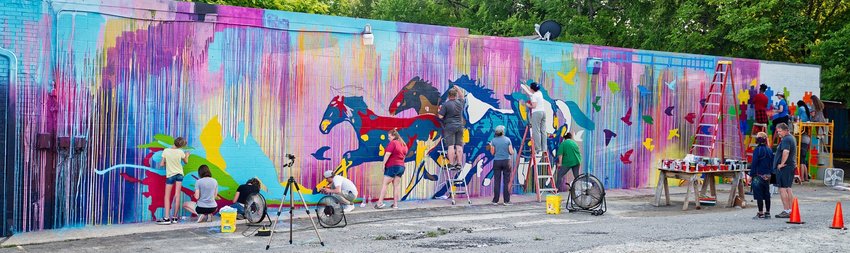 About midway through the process, volunteer muralists work Wednesday on the colorful wall on south Pacific.