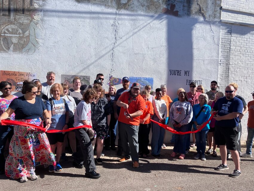 Aaron Cavitt snips the ribbon dedicating the new Artist Alley in downtown Mineola Saturday morning.