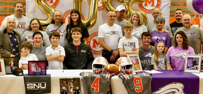 Colton McMahon and Noah Turner &ndash; seated at the table in SNU and Nelson gear respectively &ndash; are joined by members of their extended families at the signing ceremony conducted Tuesday at Mineola High School.